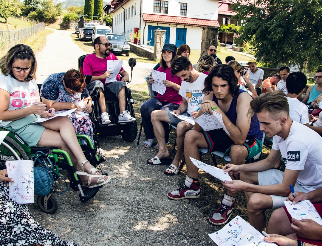 Participants sitting in a circle, writing and drawing