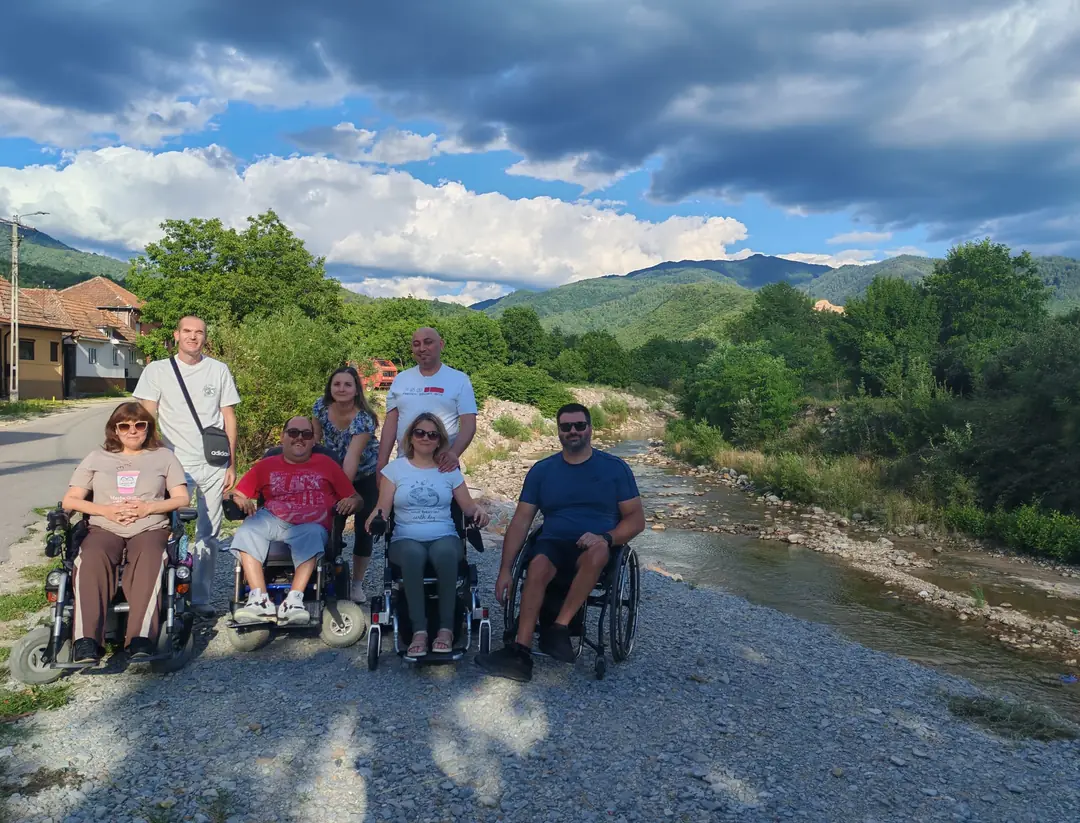 A group on a riverbank, surrounded by mountains