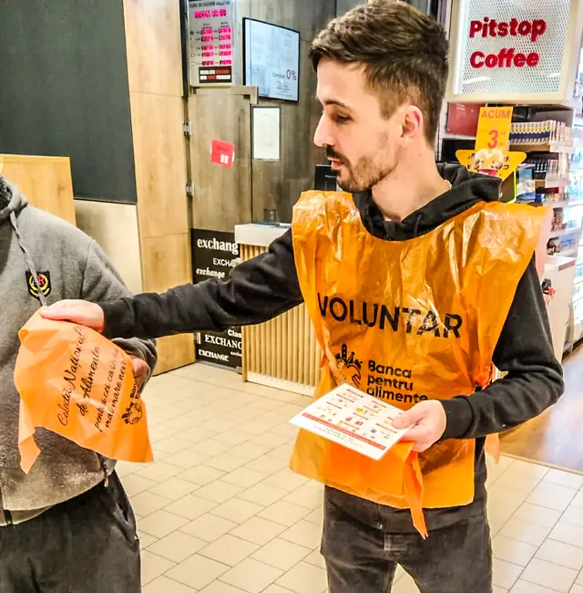 Un voluntar oferă un pliant la colecta de alimente