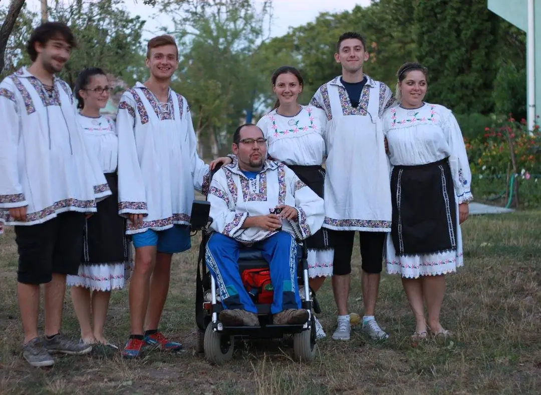 Young people in folk costumes alongside a participant in a wheelchair